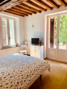 sypialnia z łóżkiem, telewizorem i oknami w obiekcie Appartamento vista Rocca w mieście Sala Baganza