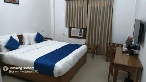a bedroom with a bed and a desk and a television at The Camellia in Dibrugarh