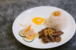 un plato de comida con arroz, carne y huevos en The Manaoag Hotel, en Manaoag