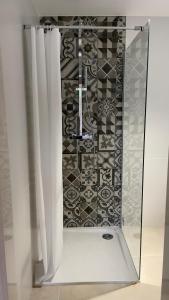 a shower with white curtains and a tile wall at DUPLEX - VALBONNE VILLAGE in Valbonne