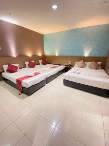 um quarto com 2 camas e almofadas vermelhas em DJ Citi Point Hotel em Kuala Terengganu