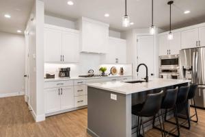 a kitchen with white cabinets and a kitchen island with black chairs at Desert Daydream townhouse in St. George
