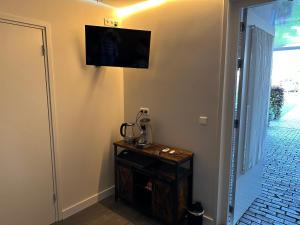 Habitación con TV en la pared y mesa. en Bed&Breakfast de Hooimoat, en Losser