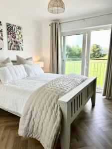 a bedroom with a white bed and a large window at Machynys Peninsula Home-Beach/Golf/Cycle- Llanelli in Llanelli