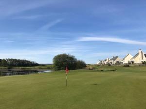 un campo de golf con una bandera en medio de un green en Machynys Peninsula Home-Beach/Golf/Cycle- Llanelli, en Llanelli