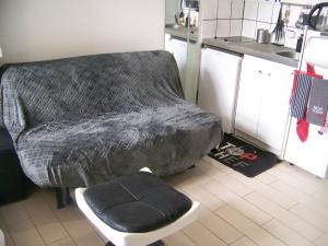 a couch in a kitchen with a stool and a chair at Charmant STUDIO au Calme Tout Confort Dans Château Néo Gothique proche ZENITH COMET ORLEANS Parking Voiture Gratuit WIFI Haut Débit Rue des Montées in Orléans