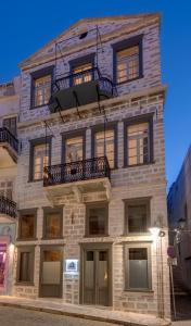 - un grand bâtiment en briques avec des fenêtres et un balcon dans l'établissement The Ten Syros, à Ermoúpoli