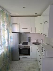 a white kitchen with a sink and a refrigerator at Comfort in Daugavpils
