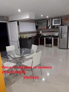 a kitchen with a glass table and white chairs at Casa zona sur mar del plata in Mar del Plata