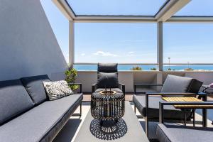 a balcony with a couch and chairs and the ocean at Apartments Blue Maris Žnjan in Split