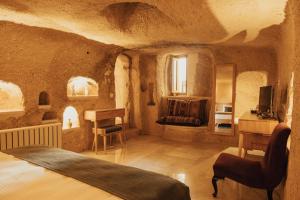 a bedroom with a bed and a desk in a cave at Juno Cappadocia Adults Only in Uçhisar