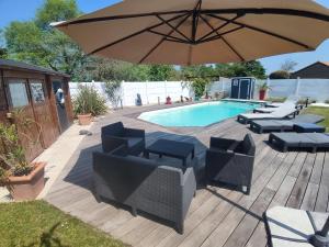 un patio con ombrellone e sedie e una piscina di Chez Daniel & Catherine a La Chevrolière