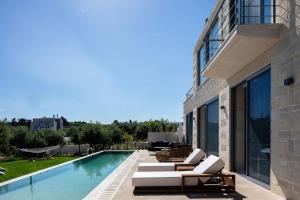 a patio with lounge chairs and a swimming pool at Heniochos Villas in Chania Town