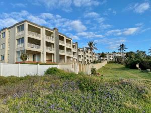 an apartment building on the beach with purple flowers at Laguna La Crete 26 in Uvongo Beach