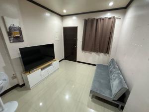 uma sala de estar com um sofá e uma televisão de ecrã plano em The Townes Davao Townhouses em Davao