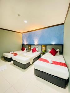 a hotel room with two beds with red pillows at DJ Citi Point Hotel in Kuala Terengganu