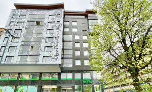 um edifício alto com uma árvore em frente em Tammer Huoneistot - City Suite 5 - Own Sauna, Balcony & Best Location em Tampere