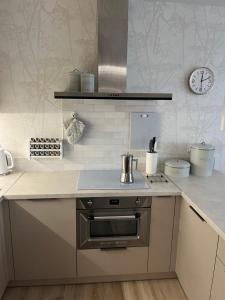 a kitchen with a stove and a clock on the wall at Apartament Akademicka in Białystok