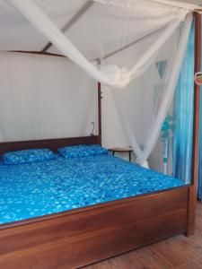 a bedroom with a wooden bed with blue sheets at Kalimetiya Beach Cabana in Hungama