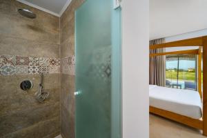 ein Bad mit Dusche und ein Bett in einem Zimmer in der Unterkunft Absolute Kiotari Resort in Asklipiḯon