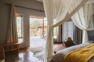 a bedroom with a canopy bed and a room with windows at Makongo Hills Lodge in Magudu