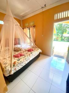 a bed with a net in a room with a window at Sumatra Cheeky Monkeys in Bukit Lawang