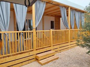 a house with a wooden deck with blue curtains at Mobile home Blue Wave in Drage