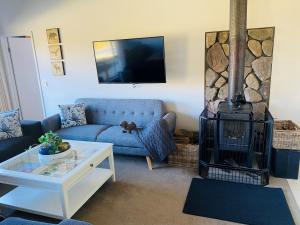 a living room with a blue couch and a fireplace at ELM Accommodation - Merrijig in Merrijig