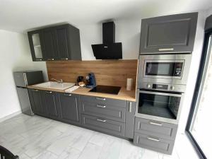 a kitchen with gray cabinets and a sink and a microwave at Maison entière lignol-le-château in Lignol-le-Château