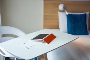 - une table blanche avec un livre et un ordinateur portable dans l'établissement Kyriad Le Mans Est, au Mans