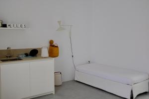 a white bedroom with a bed and a sink at MILORA SuNSET in Pollonia