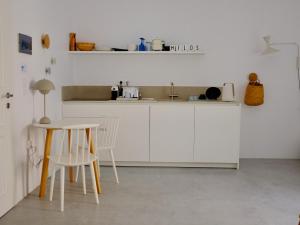 a kitchen with white cabinets and a table and chairs at MILORA SuNSET in Pollonia