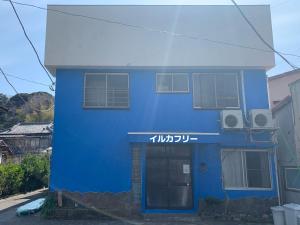 un bâtiment bleu avec des écritures sur son côté dans l'établissement 海豚自由 イルカフリー Free dolphin, à Shimoda