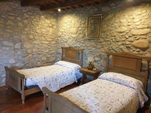 1 dormitorio con 2 camas y pared de piedra en Can More El Pasteral, en La Cellera de Ter