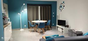 ein Wohnzimmer mit einem Tisch und blauen Wänden in der Unterkunft Appartement au centre ville de BACCARAT en RDC in Baccarat
