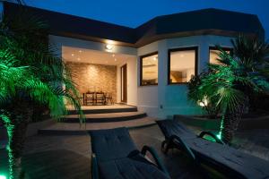 a house with two benches and palm trees in front of it at Maia Luxury Pool Villa in Afantou