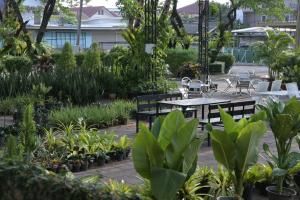 a garden with tables and chairs and plants at Rattana Park Hotel in Phitsanulok