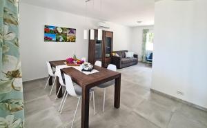 a dining room with a wooden table and white chairs at Villa Bettina in Sarroch