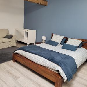 een slaapkamer met een groot houten bed met blauwe kussens bij Albizia rouge - Gîte de charme à la campagne in Galgon