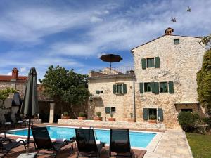 a pool in front of a building with chairs and an umbrella at Neroli Place in Svetvinčenat