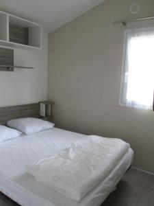 uma cama branca num quarto com uma janela em Camping Val de Boutonne em Saint-Jean-dʼAngély