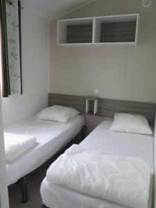 - 2 lits dans une chambre avec des draps blancs dans l'établissement Camping Val de Boutonne, à Saint-Jean-dʼAngély