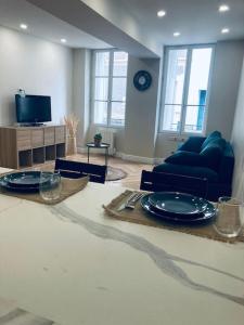 una sala de estar con una mesa con platos y un sofá en Le Cottage du Château - INSEAD-Grand Parquet, en Fontainebleau