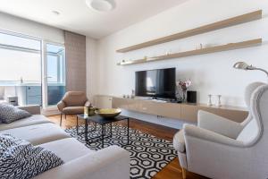 a living room with white furniture and a flat screen tv at Apartments Blue Maris Žnjan in Split