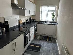 a small kitchen with white cabinets and a window at Safari Avenue one Bedroom Apartment in Stapleford