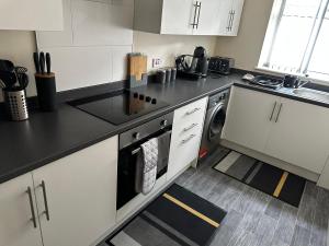 a kitchen with white cabinets and a black counter top at Safari Avenue one Bedroom Apartment in Stapleford