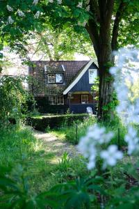 a brick house with a tree and flowers in the foreground at LooSan Lodges Gastenhuis in Reutum