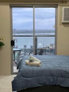 a bed with a towel on it in front of a window at Bay View Apartment Sunvida Tower 28 in Cebu City +14 photos
