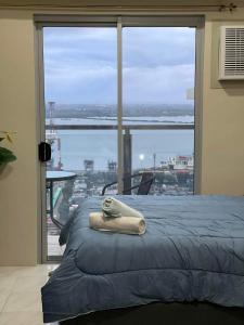 a bed with a towel on it in front of a window at Bay View Apartment Sunvida Tower 28 in Cebu City
