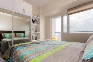 sypialnia z 2 łóżkami i dużym oknem w obiekcie Blowing in the Wind - Lake View Apartments w mieście Tagaytay